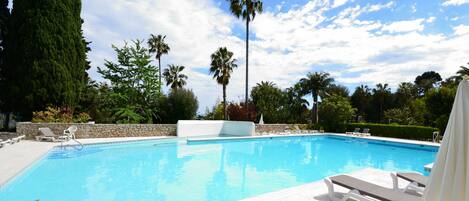 Una piscina con lettini e un muro in pietra.