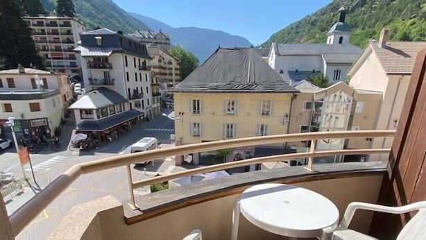 A balcony with a view of a town, including buildings and a mountain in the background.