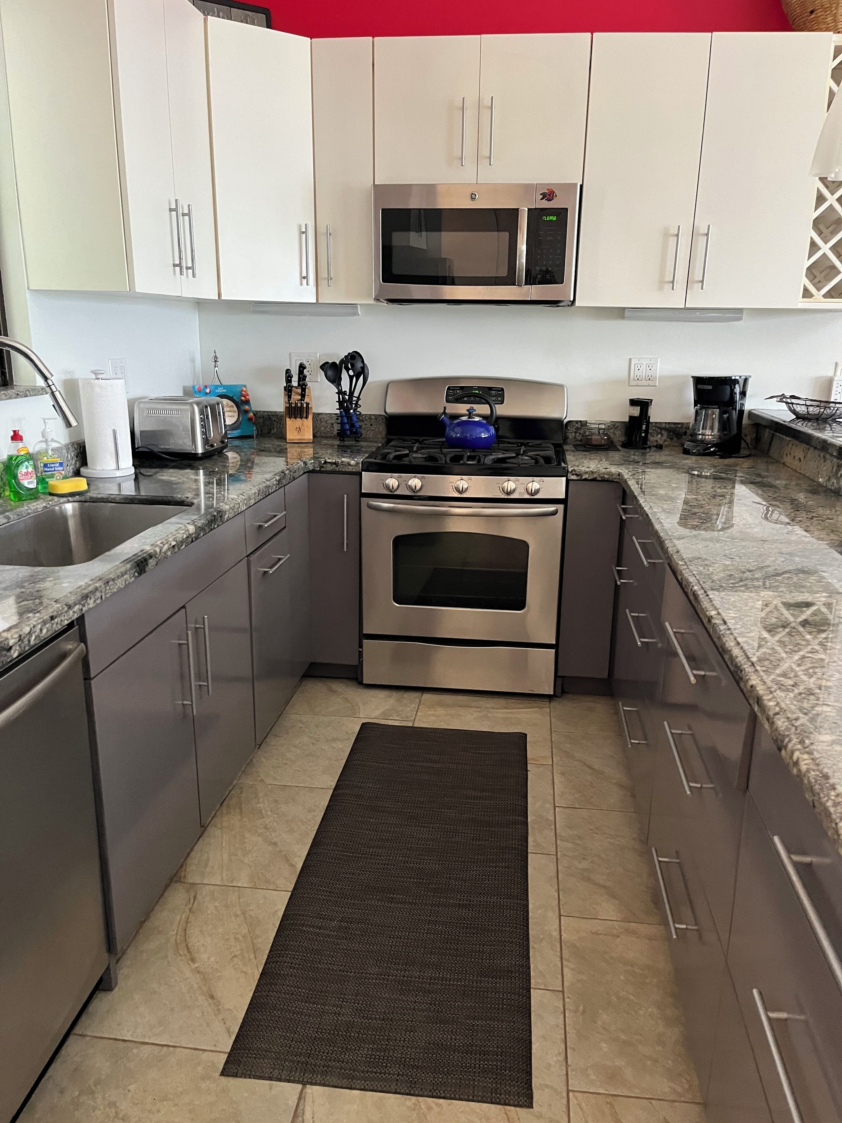 A kitchen with stainless steel appliances, a microwave, a toaster, and a gas stove.