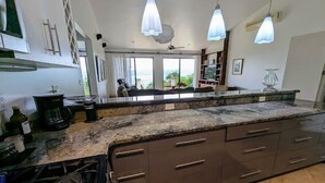 A modern kitchen with granite countertops, dark cabinetry, and pendant lighting. - Stunning views of Lake Arenal & Volcano in Secure Safe Gated Vacation Community (Tronadora)