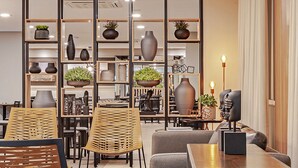 A modern interior with seating, a coffee table, and decorative items. - SLAVIERO Curitiba Aeroporto (Sao Jose dos Pinhais)