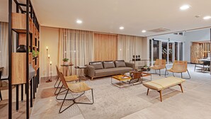 A modern living room with a sofa, chairs, a coffee table, and a bookshelf. - SLAVIERO Curitiba Aeroporto (Sao Jose dos Pinhais)