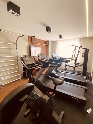 A home gym with a treadmill, stationary bike, and weight machine. - SLAVIERO Curitiba Aeroporto (Sao Jose dos Pinhais)