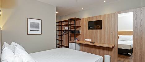 Une chambre d’hôtel moderne équipée d’un grand lit, d’un bureau avec un ordinateur, d’une armoire et d’une télévision.