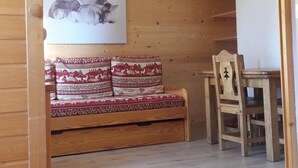 Ein Holzinterieur mit einer Couch, einem Esstisch und einer Deckenleuchte.