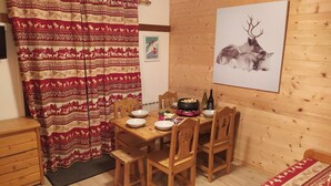 Ein Holzespeisesaal mit Stühlen, einem Bilderrahmen mit einem Reh und einem roten, gemusterten Vorhang.