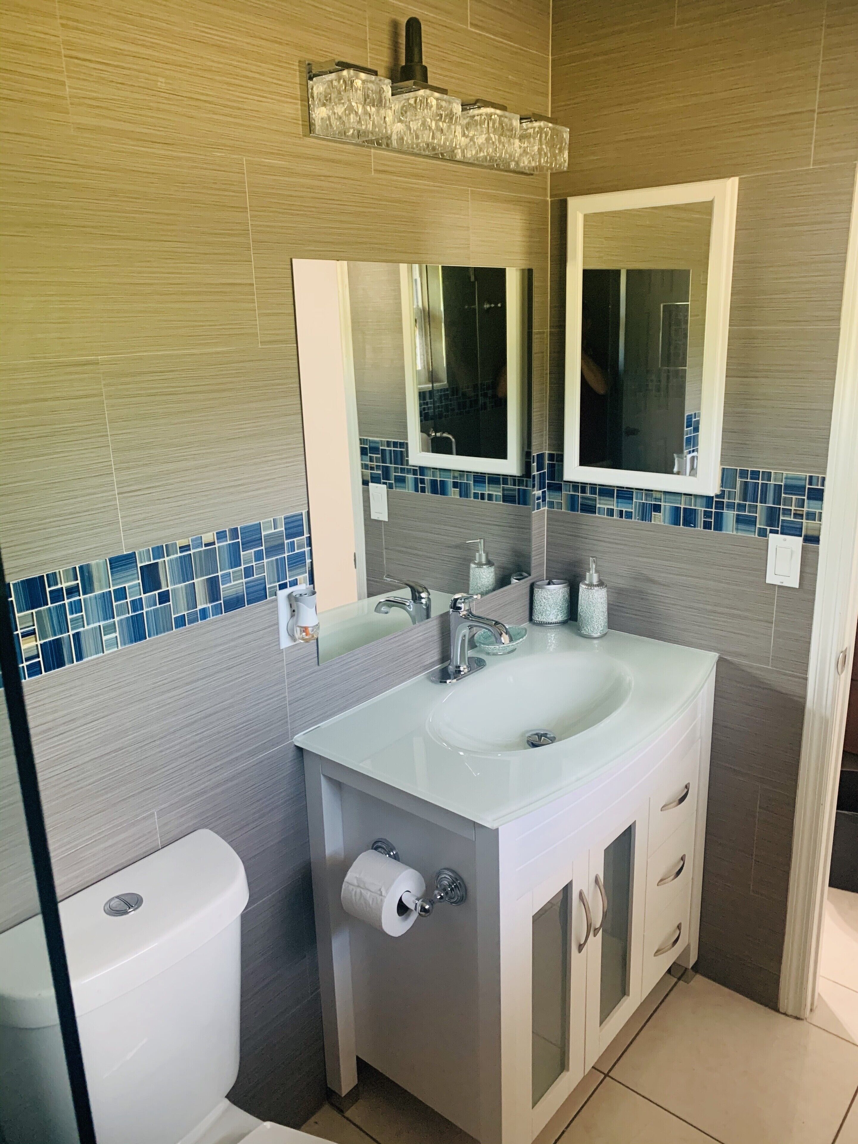 Un bany modern amb un lavabo, mirall i vàter blancs.