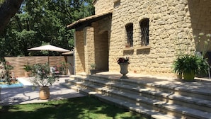 A stone building with a pool, steps leading to the entrance, and potted plants.