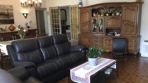 A living room with a black leather sofa, a coffee table with a decorative cloth, and a wooden cabinet with glass doors.