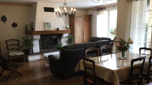 A cozy living room with a fireplace, a dining table with chairs, and a black leather sofa.