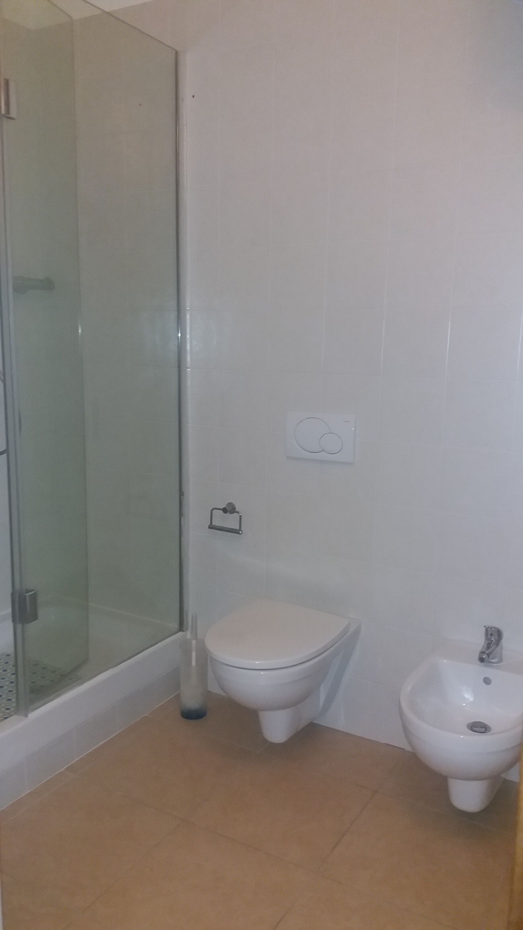 A bathroom with a glass shower enclosure, a toilet, and a bidet.