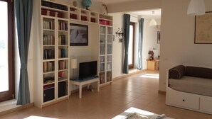 Una sala de estar con estantería, televisor, sofá y mesa de centro.