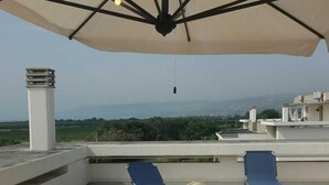 Terraza en la azotea con mesa y sillas, una lámpara colgante y vistas al paisaje.