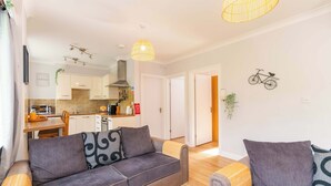 A modern living room with a sofa, a smaller couch, and a dining area with a kitchen in the background. - The Nook at Afan Forest Park by STAE-Homes (Duffryn Rhondda)