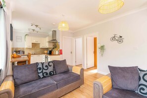 A modern living room with a sofa, a smaller couch, and a dining area with a kitchen in the background. - The Nook at Afan Forest Park by STAE-Homes (Duffryn Rhondda)