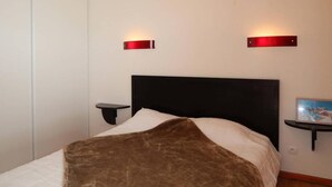 Une chambre à coucher comprenant un lit, deux tables de chevet et des lampes fixées au mur.