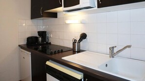 Une cuisine compacte équipée d’un four à micro-ondes, d’une cuisinière, d’un évier et d’un lave-vaisselle.
