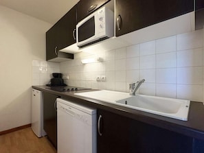 A compact kitchen with a microwave, sink, dishwasher, and a small refrigerator.