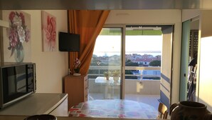 A balcony with a table, a potted plant, and a view of the cityscape. - PLEASANT STUDIO CABIN PARKING SEA AT 80M (Canet-en-Roussillon)