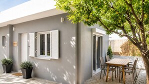 Een modern huis met een terras, een eettafel en potplanten.