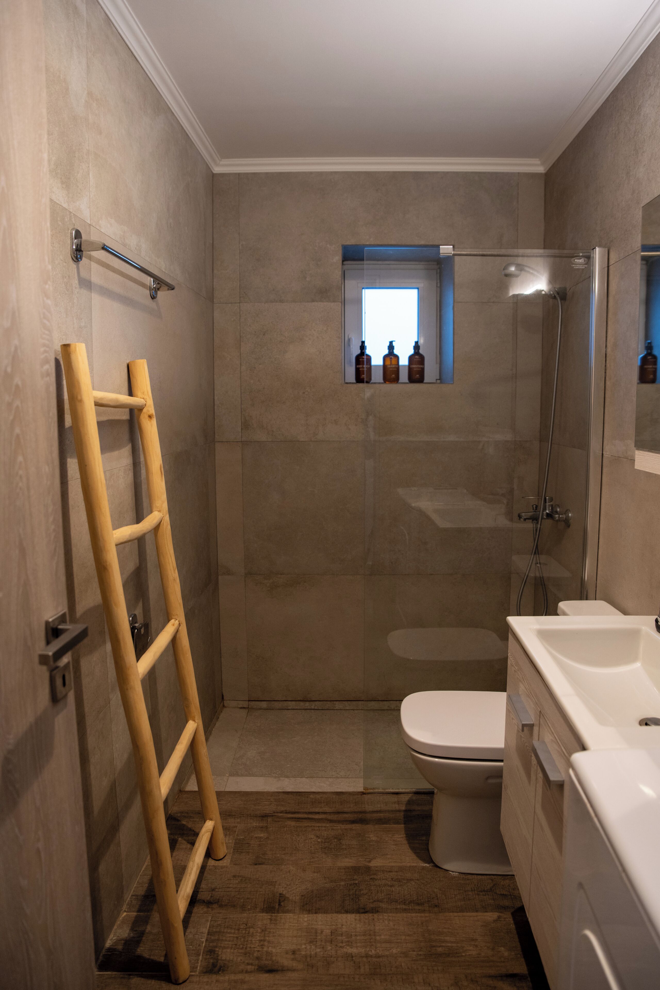 Un baño con ducha, inodoro y una escalera de madera.