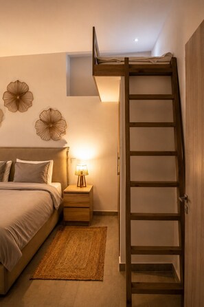 Une chambre à coucher comprenant un lit, une table de chevet, une lampe, des éléments de décoration murale et une échelle en bois.