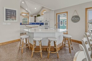 Una cocina con una isla central, armarios blancos y un letrero colgante.