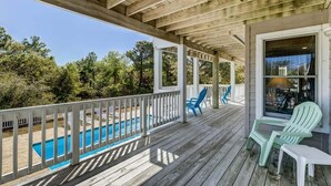 A wooden deck with a pool, outdoor seating, and a view of trees. - Duck Tales | 2400 ft from the beach | Private Pool, Hot Tub | Duck (Duck)