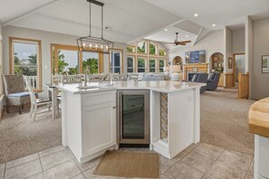 Una cocina amplia con una isla grande, un comedor con candelabro y una sala de estar con chimenea.