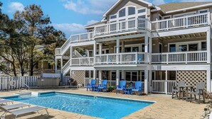 A two-story building with a swimming pool, outdoor seating, and a covered patio area. - Duck Tales | 2400 ft from the beach | Private Pool, Hot Tub | Duck (Duck)