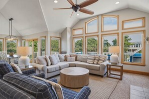 A spacious living room with a large sectional sofa, a round coffee table, and a ceiling fan. - Duck Tales | 2400 ft from the beach | Private Pool, Hot Tub | Duck (Duck)