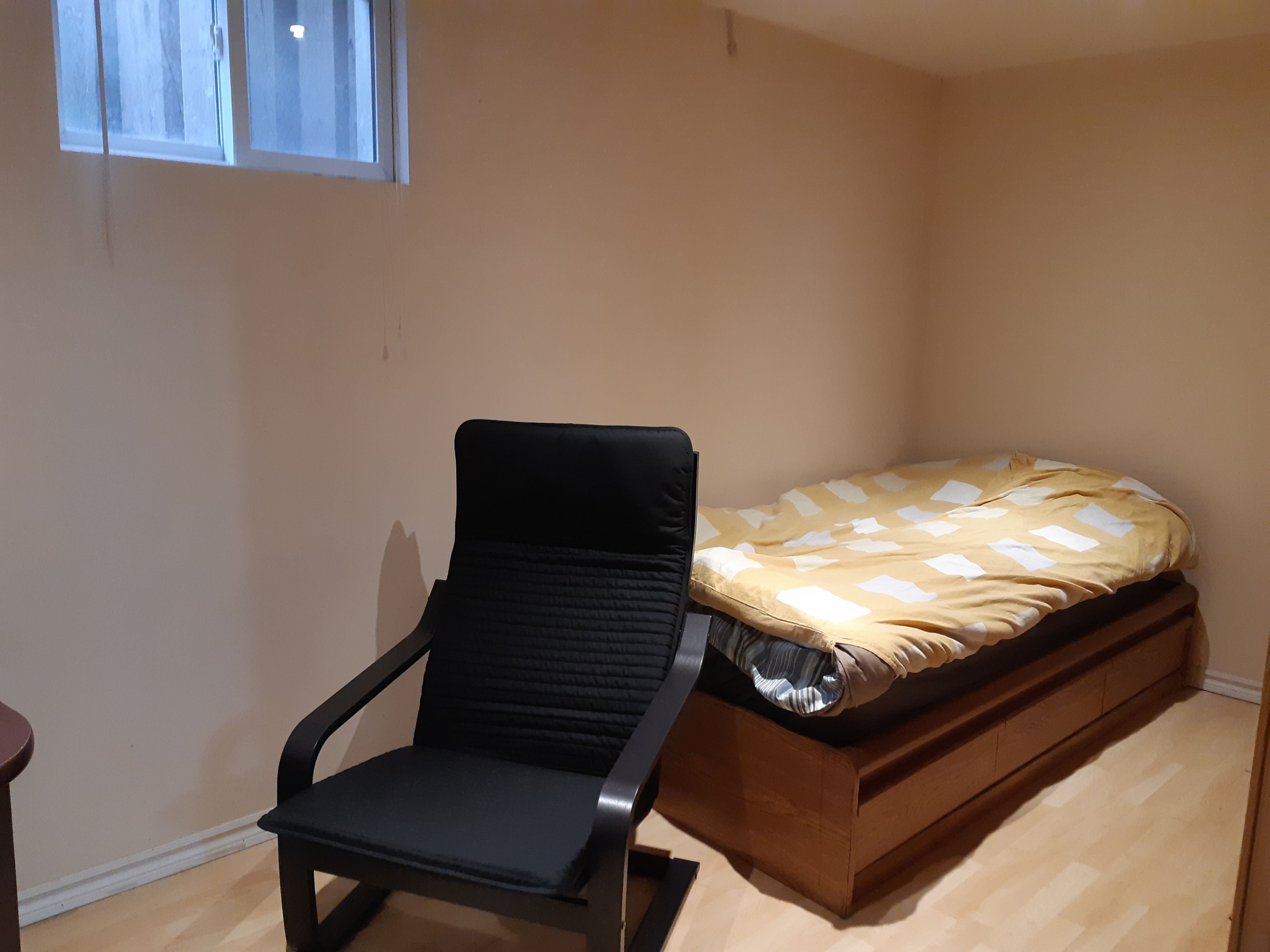 Una habitación con cama, silla y ventana.