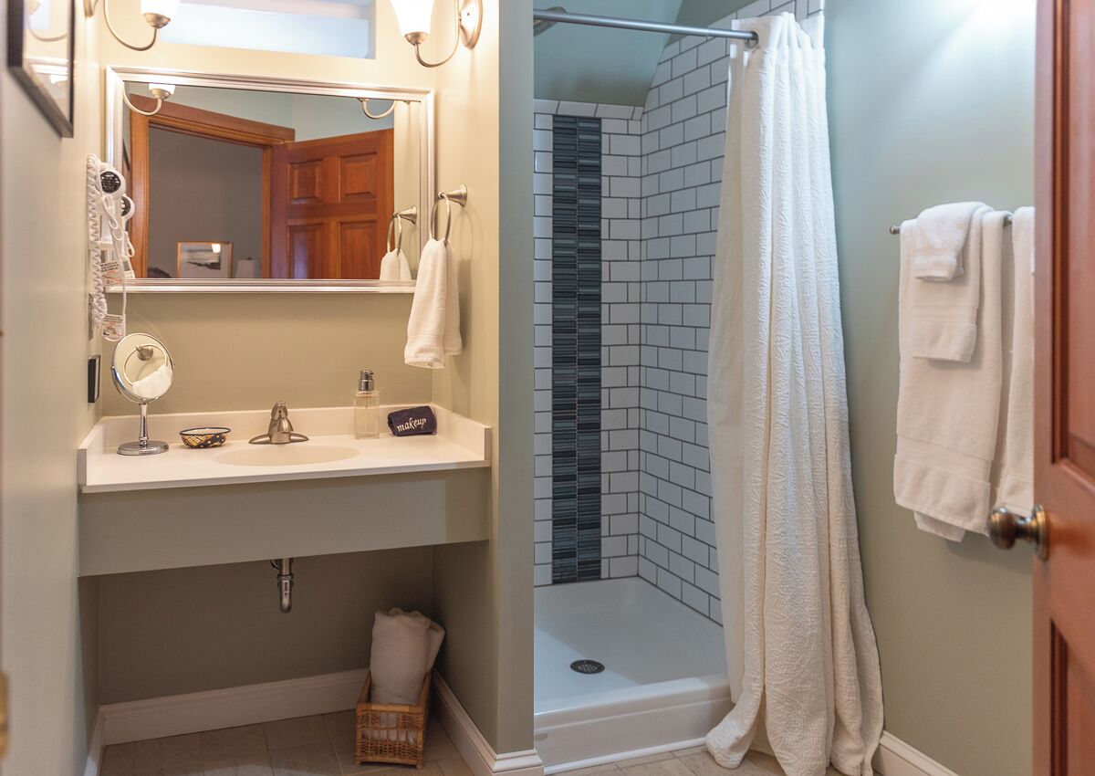Un baño con lavamanos, espejo y ducha.