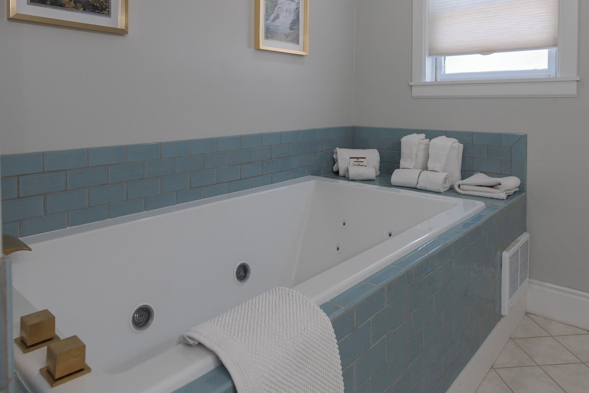 Une salle de bain moderne avec une grande baignoire, des murs recouverts de carreaux bleus et des serviettes soigneusement rangées.