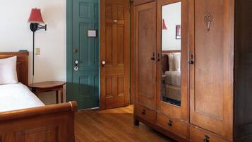 A bedroom with a wooden bed, a green door, and a large wooden wardrobe with a mirror.