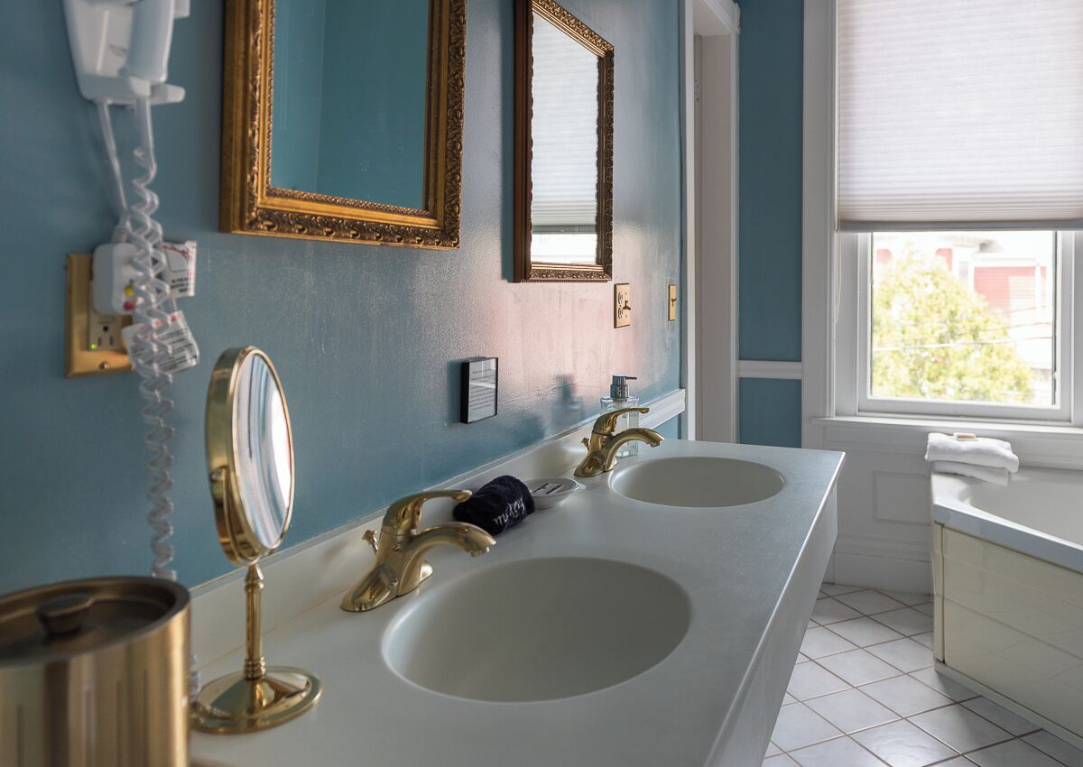 A bathroom with two sinks, a mirror, and a telephone.