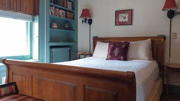 A bedroom with a wooden bed, a bookshelf, two wall lamps, and a framed picture on the wall.