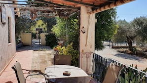 Ein Balkon mit Tisch und Stühlen, umgeben von einem Garten und Blick auf eine Straße.