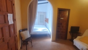 Ein Hotelzimmer mit einem Bett, einem Sessel, einer Couch und einer Holztür mit einem Schild.