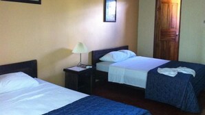 A room with two beds, a nightstand with a lamp, a framed picture on the wall, and an air conditioning unit. - Hotel Arbol Dorado (Florencia)