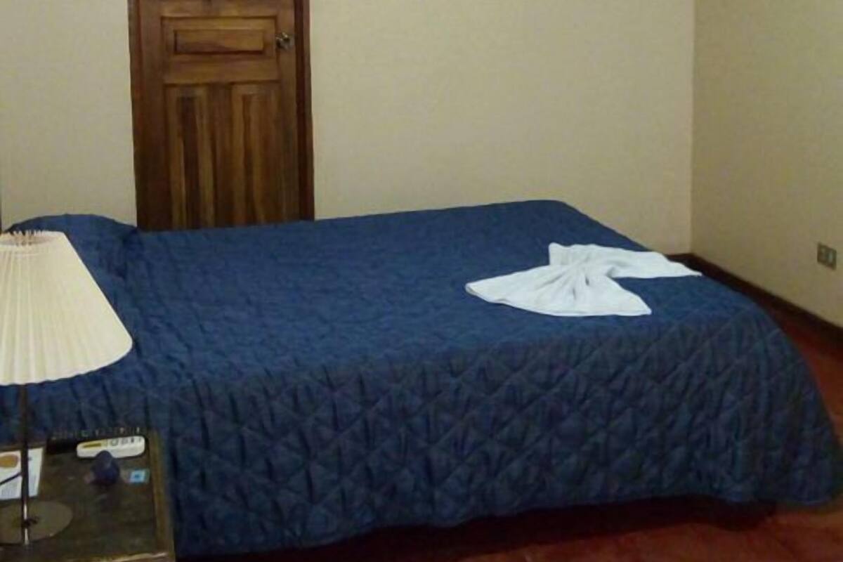 Ein Schlafzimmer mit zwei Betten, einer Holztür, einem an der Wand montierten Fernseher und einer Klimaanlage.