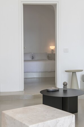 A minimalist room with a bed, a round table, and a small table with a lamp.