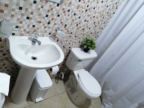 A bathroom with a white sink, toilet, and a tiled backsplash. - Anedi Guesthouse (La Vega)