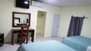 Habitación de hotel con dos camas, un escritorio, una silla, un televisor y un equipo de aire acondicionado.