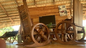 Un interior rústico de madera con techo de paja, muebles de madera y un televisor antiguo.