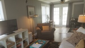 Un salon comprenant un téléviseur, un canapé, une table basse et une bibliothèque.