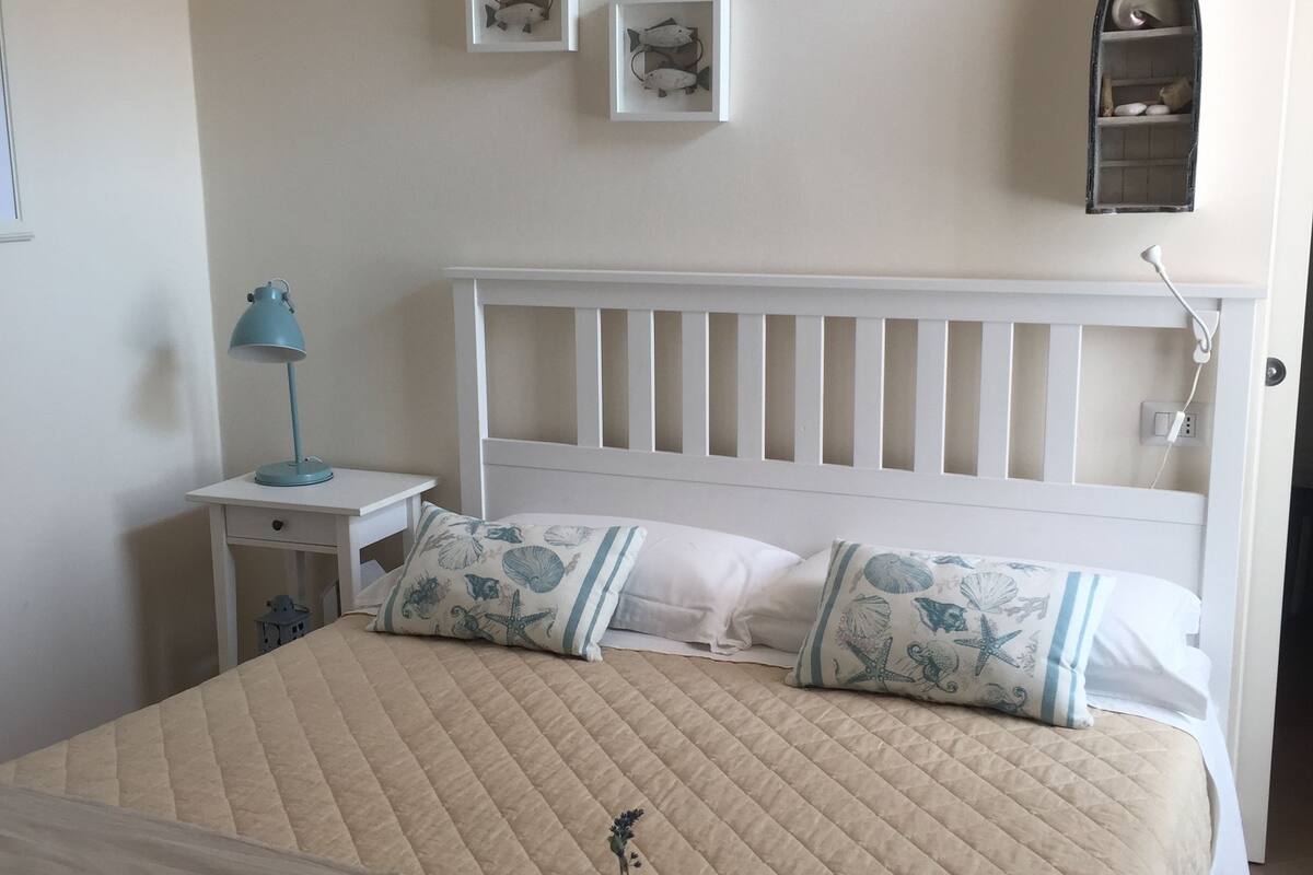Une chambre à coucher avec un lit, une table de chevet, une lampe et des œuvres d’art murales.