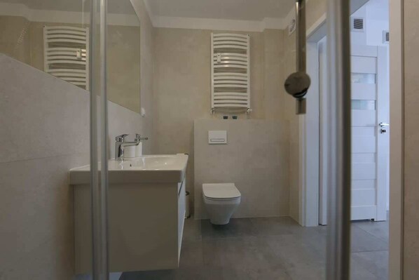 Une salle de bain équipée d’un lavabo, de toilettes et de porte-serviettes.
