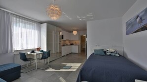 Ein modernes Schlafzimmer mit Bett, Schreibtisch und einer kleinen Küchenzeile.