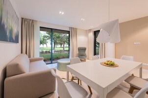 Un comedor moderno con una mesa blanca, sillas color beige y un ventanal con vistas a un parque.